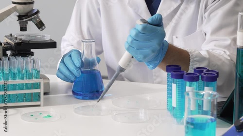 Young Caucasian male scientist works in laboratory, analyzing chemical samples with glassware and microscope. research tools, experiments, data interpretation, pharmaceutical development.