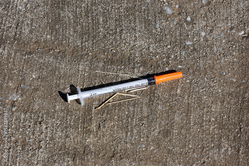 Fotografija Discarded syringe on an outdoor concrete surface
