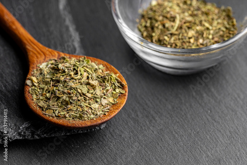 Wooden spoon with mixed dried fine herbs on a dark slate background