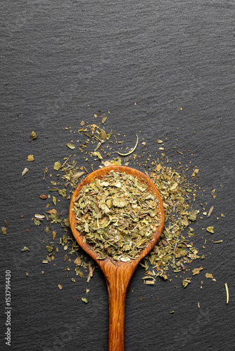 Obraz na plátně Wooden spoon with mixed dried fine herbs on a dark slate background