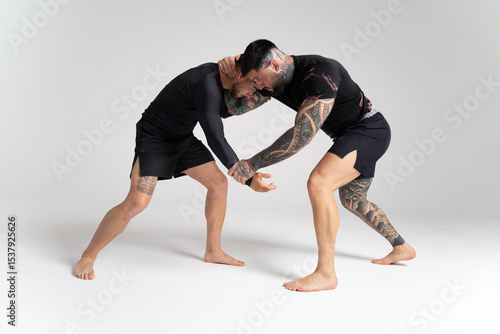 Two male wrestlers grappling in studio on white background