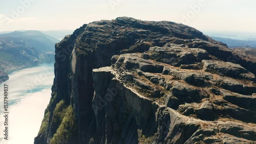 Magnificent Preikestolen with immense rock face plunging towards Lysefjord. Norwegian landscape with fjord winding through distant mountains