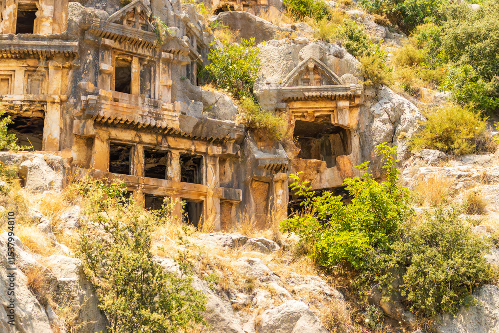 Naklejka premium Demre, Turkey - June 14, 2025:View of the ancient Lycian necropolis and Roman amphitheater in the ruins of Myra, located in Demre, Antalya Province, Turkey.