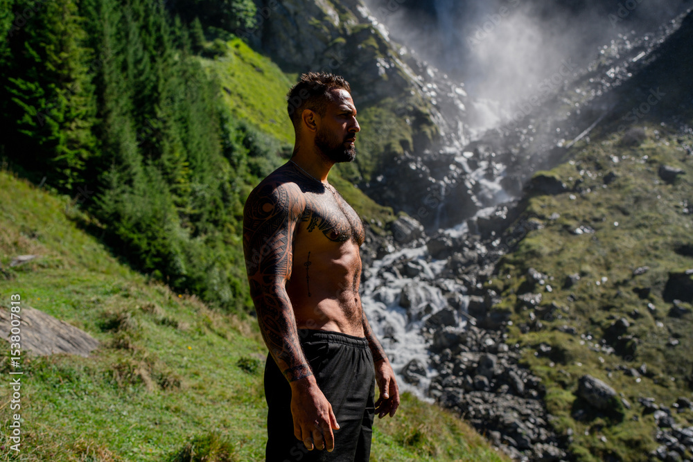Naklejka premium Man tourist on summer vacation. Handsome man with naked torso on summer vacation day. Sexy hiker outside. Tourist man walking on the waterfall landscape. Man Traveling and nature.