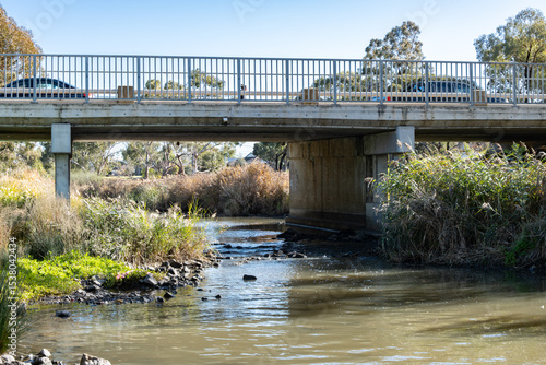 Obraz na płótnie A road bridge spans the quiet Skeleton Creek with native grasses and reeds in Melbourne’s outer suburbs