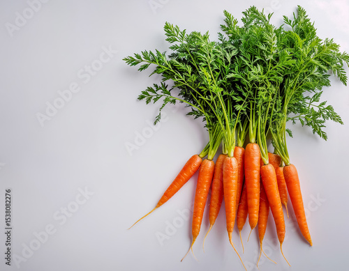 Carottes entières vue du dessus avec  fanes et racines, fond blanc uni, espace libre pour texte, coloré 