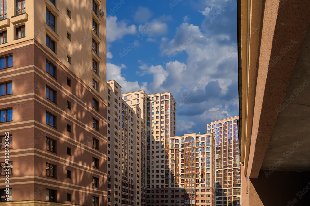 Fototapeta premium City view on a sunny day. Modern building and houses against the blue sky.