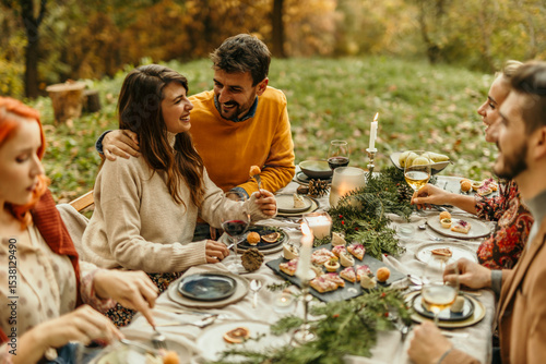 Friends enjoying thanksgiving dinner together outdoors in autumn