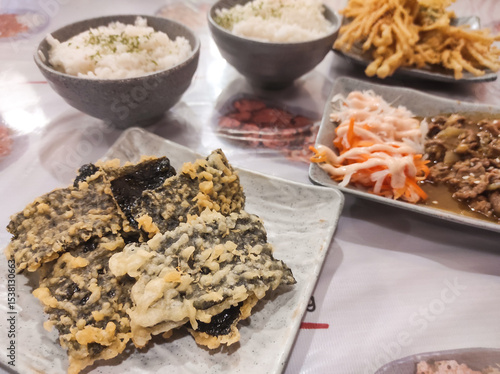Closeup shot of Japanese food dishes in a restaurant. Japanese food feast consisting of seaweed rice, Beef Yakiniku, crispy Nori and Enoki Tempura. Typical Japanese food. Food photography