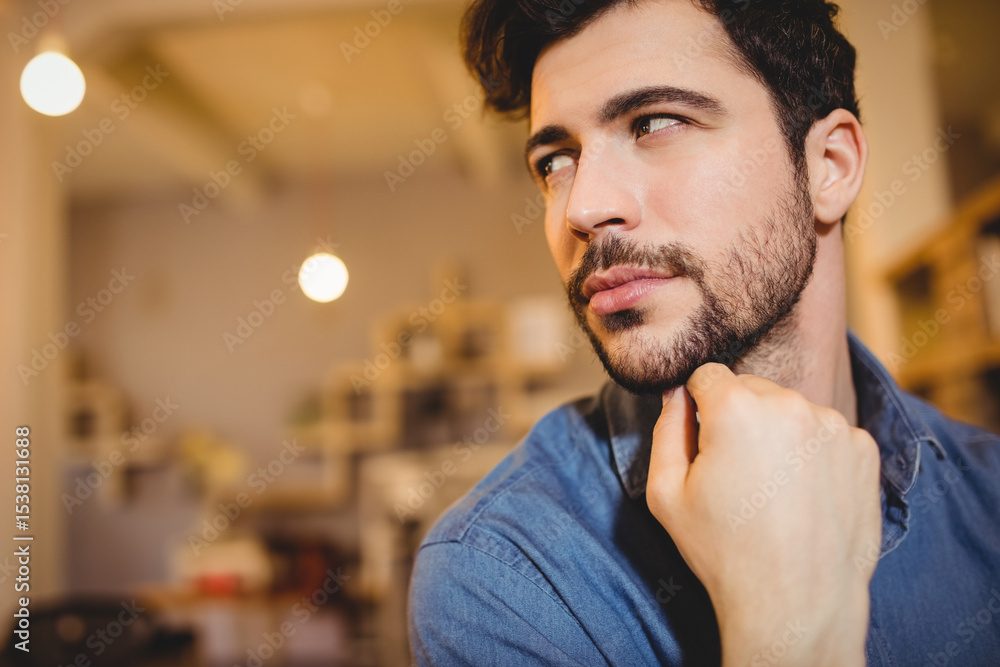 Obraz premium Man is sitting at desk in café workspace under hanging light bulbs and wooden shelves