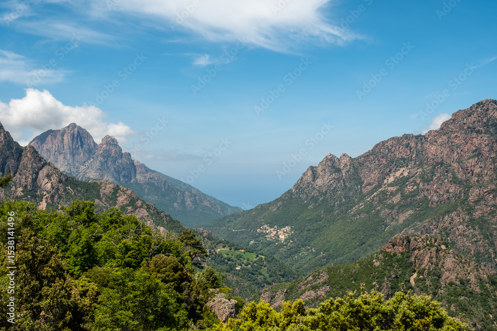 Fototapeta premium The village of Ota near the west coast of the island of Corsica with the towering peaks of Capu d'Ota and Capu d'Orto behind and the Mediterranean sea in the distance