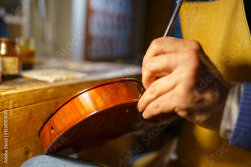 Schilderij op canvas Violinmaker carefully varnishing wooden violin body, traditional tools and varni