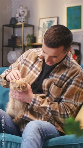 Wallpaper Mural Smiling man in brown flannel holding small kitten on lap while petting gently. Looking down affectionately while bonding with furry companion. Enjoying calm moment and stroking soft ears. Torontodigital.ca
