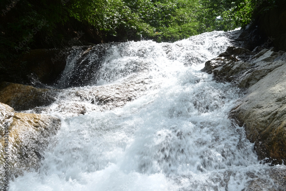 Naklejka premium Raging waterfall flowing over rocky cliffs in a lush green setting