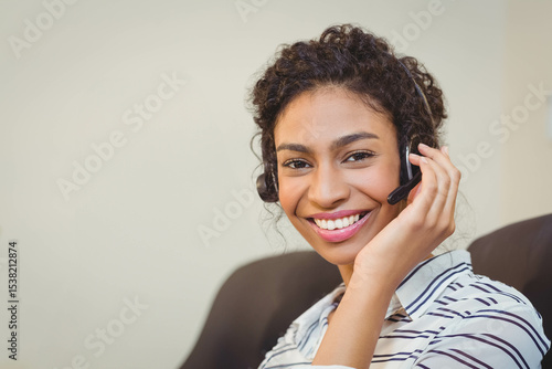 Quadro su tela Female service rep sitting on office chair in cubicle using headset mic while sm
