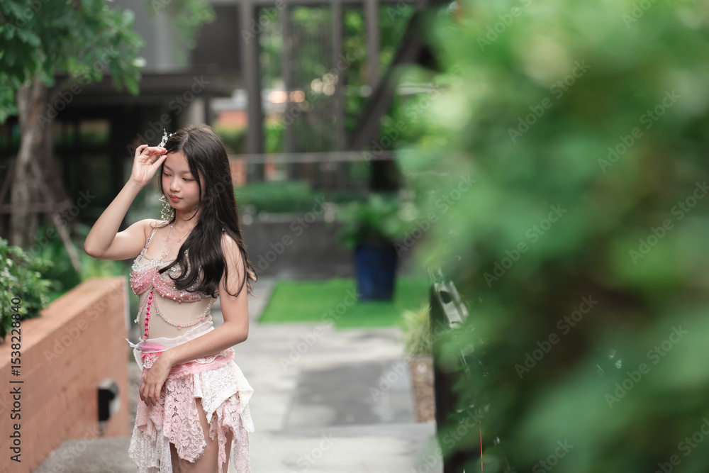 Naklejka premium Elegant woman in pink outfit posing in a lush garden setting