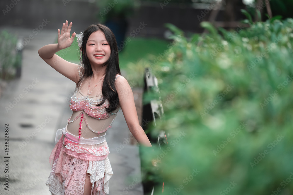 Fototapeta premium Young girl in traditional attire smiling and waving outdoors
