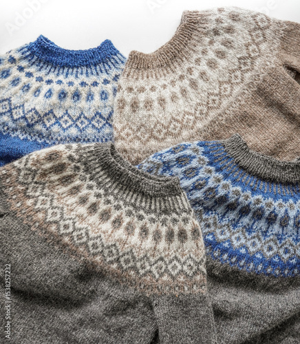 Pile of brown and blue colors Icelandic wool knitted sweaters jumpers with Nordic patterns around the neckline on white background