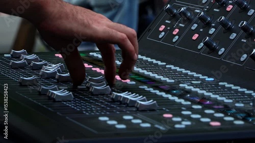 Close up of sound technician moving faders of the soundboard during summer music festival
