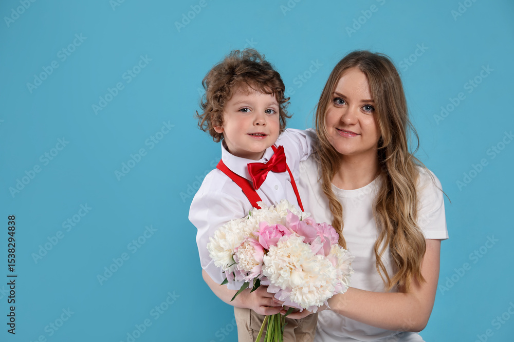 Little boy giving his mom beautiful peony flowers on light blue background Little boy giving his mom beautiful peony flowers on light blue background