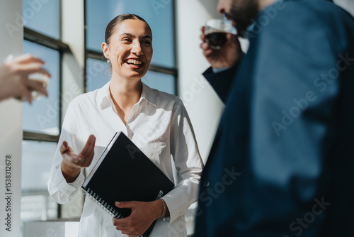 Foto Three business colleagues engage in a lively conversation while enjoying a coffee break in a bright office setting