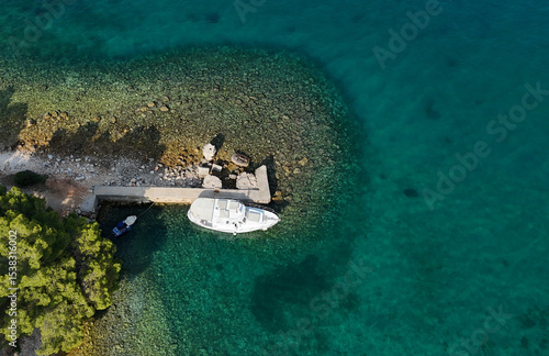 Aerial drone photo of a vacation boat in turquoise water next to a jetty in Croatia. Photography for background, postcards, wallpapers.