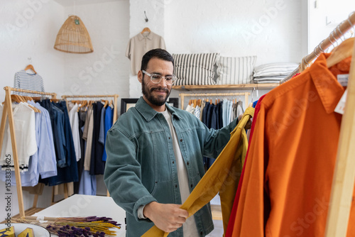 Man Examining Yellow Shirt in Clothing Store