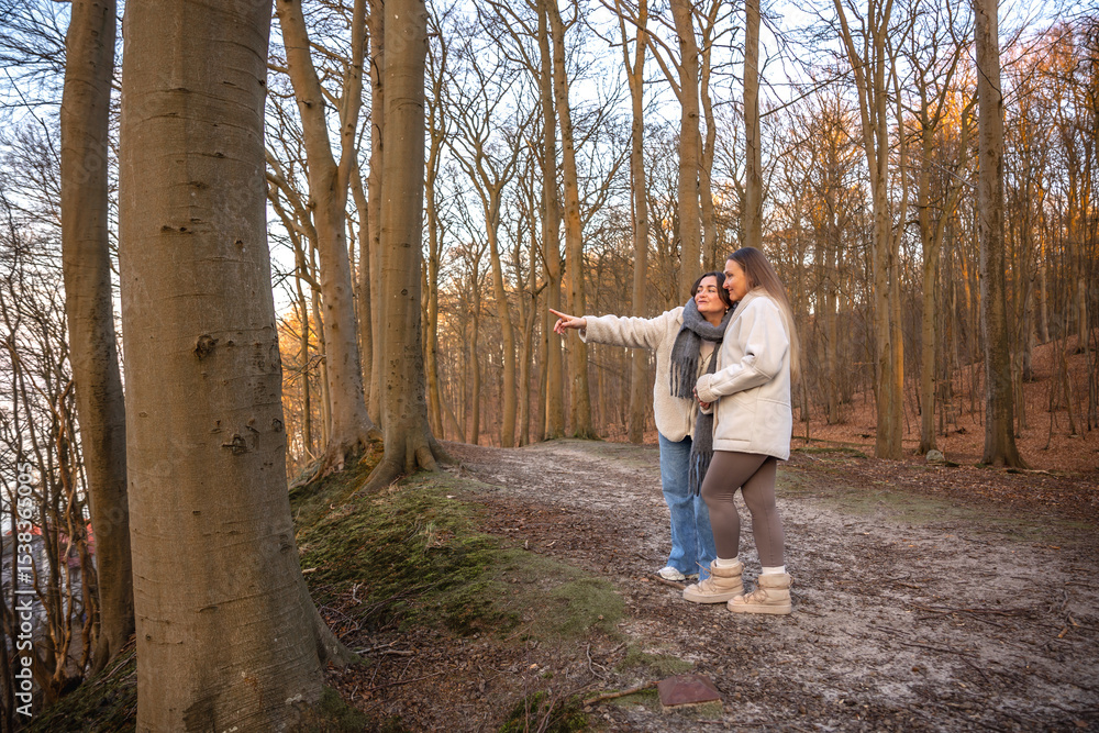 Fototapeta premium Two women in the forest. Woman pointing at the scenery. People in nature.