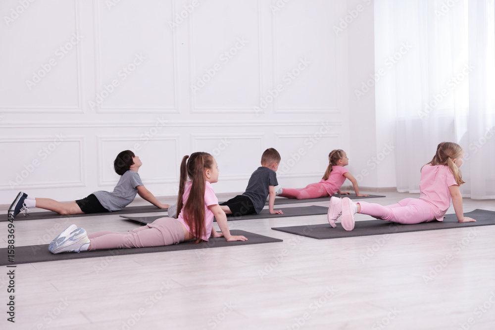 Fototapeta premium Group of children practicing yoga on mats in class