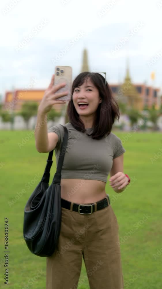 Vertical video of beautiful young asian woman 30s enjoying solo traveler trip around Bangkok, tourism blogger using smartphone to capture street journey Sanam Luang public square near Wat Phra Kaew. Vertical video of beautiful young asian woman 30s enjoying solo traveler trip around Bangkok, tourism blogger using smartphone to capture street journey Sanam Luang public square near Wat Phra Kaew.