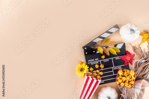 Autumn seasonal movie marathon. Cozy fall season cinema and TV-show Movie Night party. Cinema clapper-board, sweet pumpkin syrup caramel popcorn in paper cups, autumn leaves, pumpkins and decorations