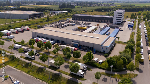 A large warehouse with many trucks parked outside. Aerial view.