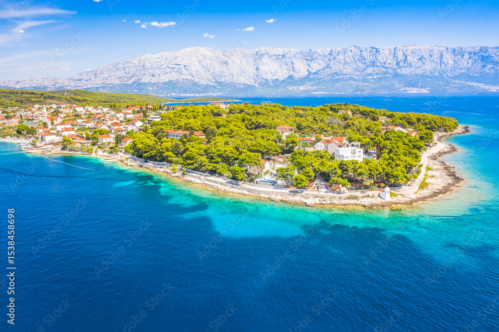 Naklejka premium Drone view of Sumartin, a picturesque coastal village on Brac Island, Croatia, captures the charming harbor, traditional stone houses, and crystal-clear waters of the Adriatic Sea