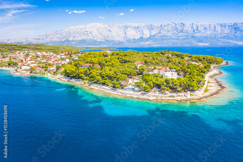 Drone view of Sumartin, a picturesque coastal village on Brac Island, Croatia, captures the charming harbor, traditional stone houses, and crystal-clear waters of the Adriatic Sea