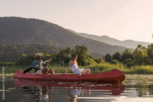 Slika na platnu Couple spending a hot summer afternoon on the lake, gently paddling a canoe on calm water
