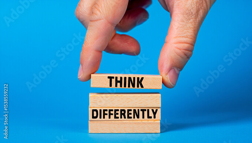 A hand places a wooden block with the word think on top of a stack of blocks that read differently