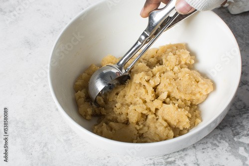 scooping vanilla cookie dough in a white mixing bowl, process of making vanilla cookie dough