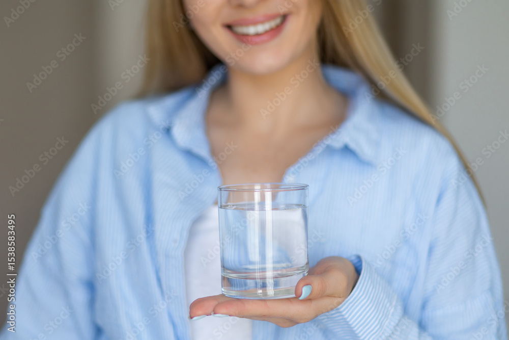 Smiling woman offering a refreshing glass of water indoors Smiling woman offering a refreshing glass of water indoors
