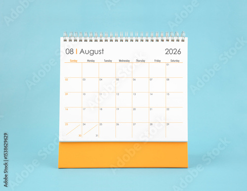 August 2026 white desk calendar on blue color background. Planning and goals concepts.