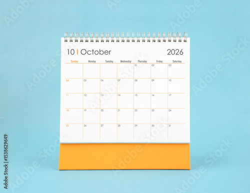 October 2026 white desk calendar on blue color background. Planning and goals concepts.