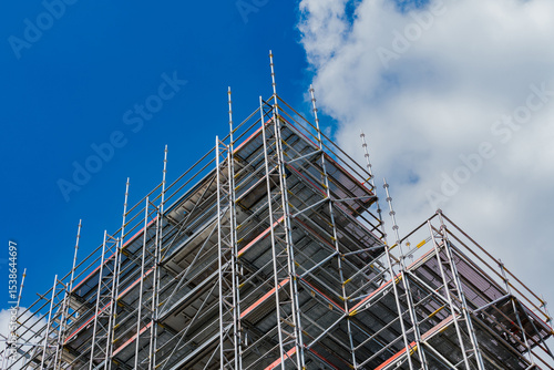 Construction scaffolding against a blue sky with clouds