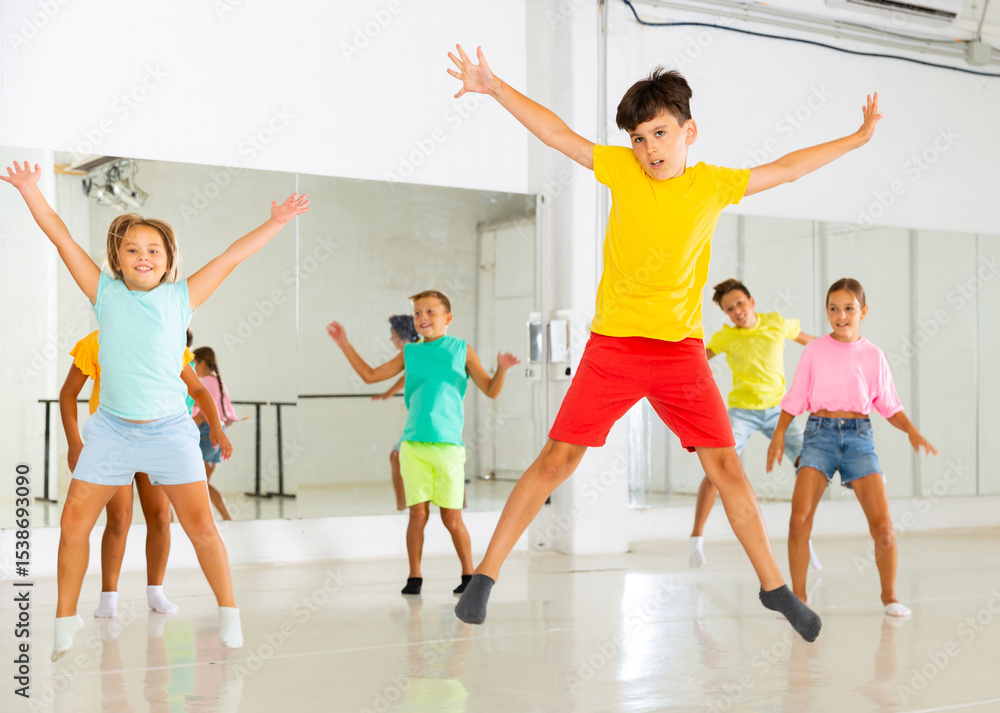 Naklejka premium Group of positive kids jumping while dancing together in studion.