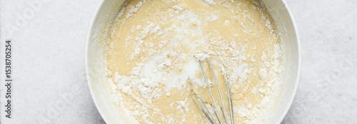 Overhead view of flour being mixed into cake batter, top view of vanilla cake batter being mixed, process of making vanilla cake