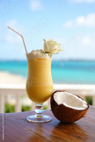 A refreshing tropical drink a pina colada on a wooden table by beach.