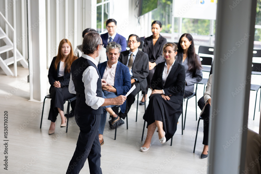 Fototapeta premium Back view speaking training in seminar : Senior caucasian business man leader in seminar, speaking on business training with group of diverse people company employees in meeting room