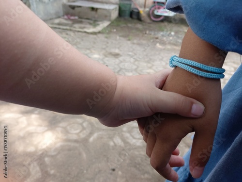 A touching moment of two children holding hands, symbolizing love, care, friendship, and sibling bond.