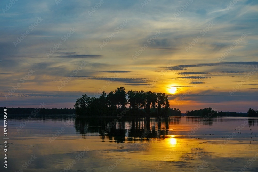 Obraz premium Sunset over a tranquil lake with an island silhouette