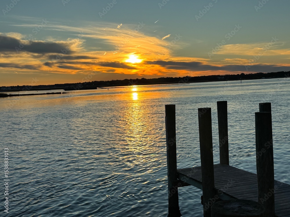 Fototapeta premium Wooden dock at golden sunset over quiet bay