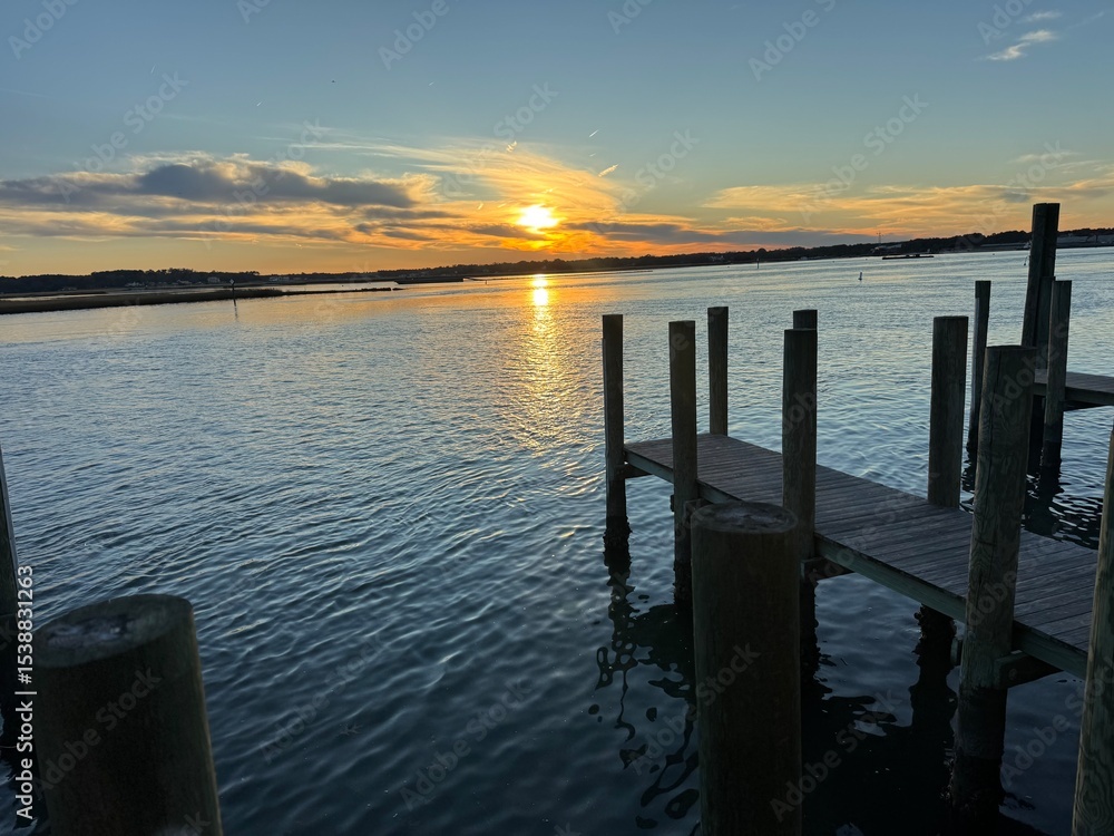 Obraz premium Wooden dock at golden sunset over quiet bay