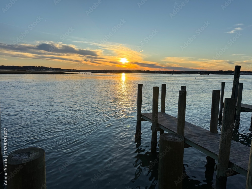 Obraz premium Wooden dock at golden sunset over quiet bay